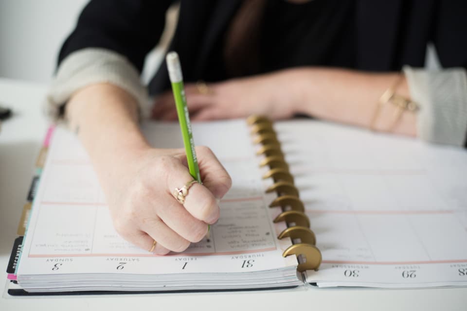 手帳に予定を書き込む手元 — 学習の出口(渡航先や目標級)を先に決めるゴール設定のイメージ
