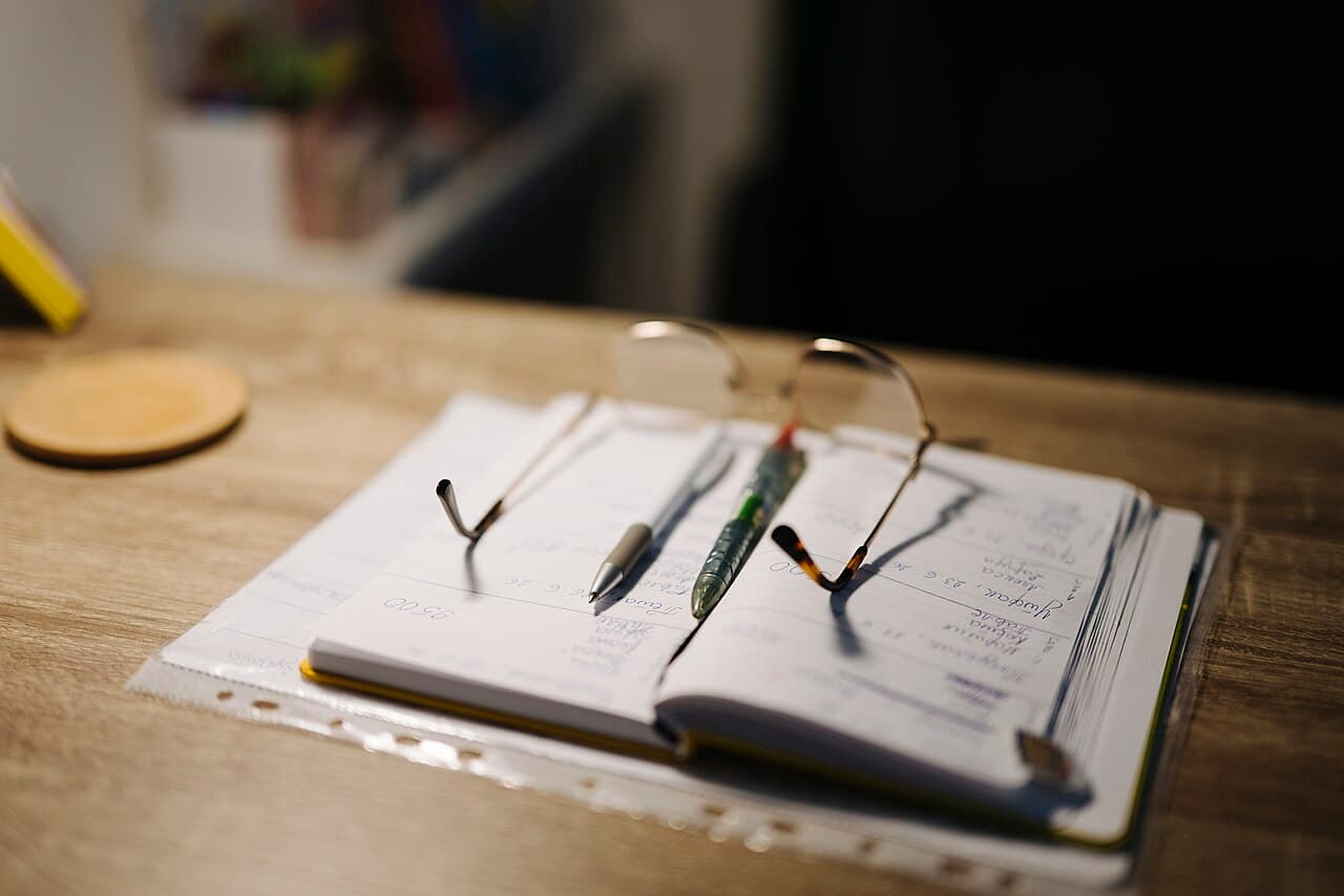 ノートとペン、メガネが置かれた学習机 — スペイン語独学の学習計画づくりをイメージした一枚