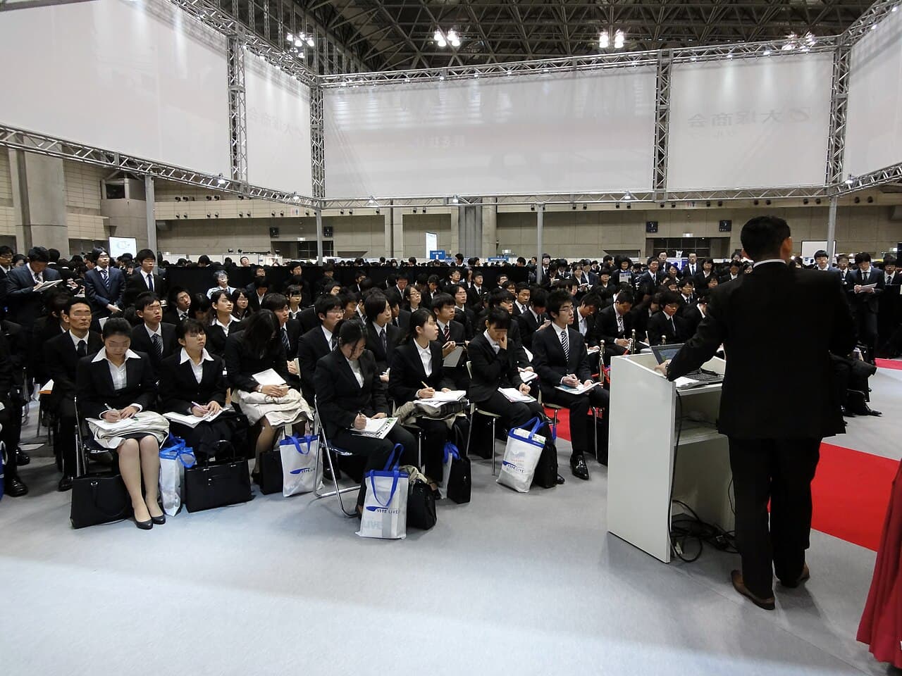 日本の企業説明会でリクルートスーツ姿の学生たちが着席している様子